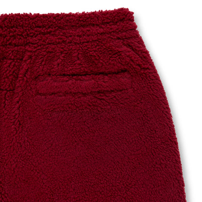 Close-up of a burgundy sherpa fleece pant showing the textured material and back pocket.