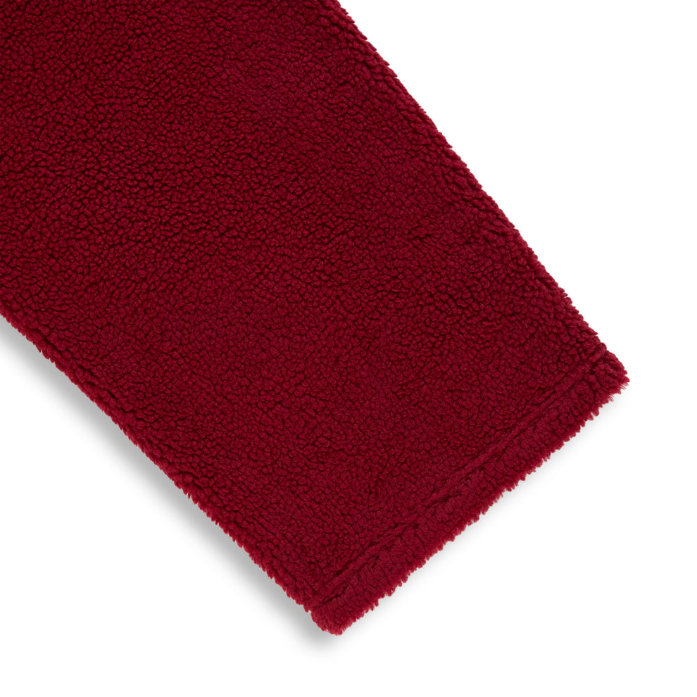 Close-up of a rich red sherpa fleece pant leg, showing the soft, textured material.
