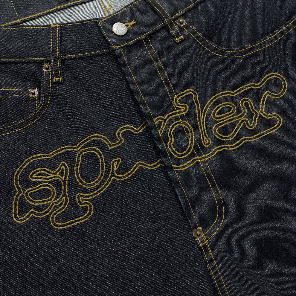 Dark wash denim jeans with yellow embroidered "SP5DER" logo across the crotch.