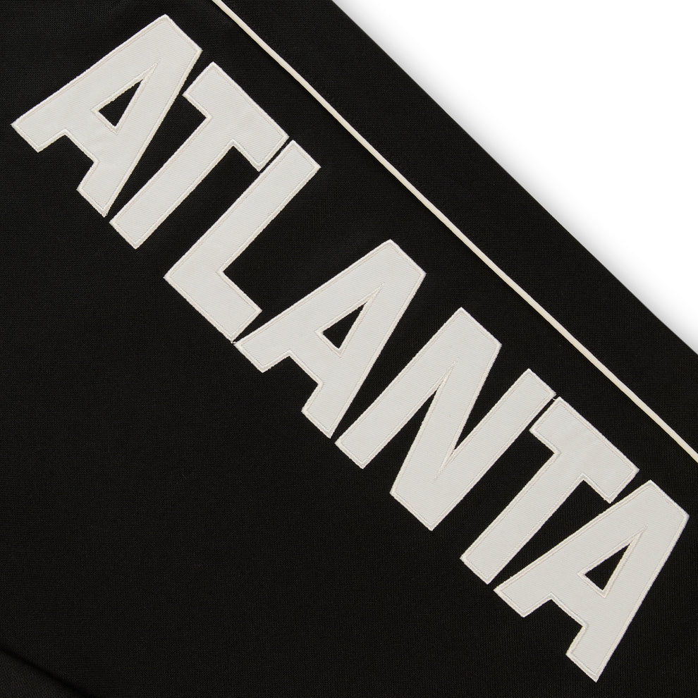 Black ATLANTA TRACK PANT with bold white "ATLANTA" graphic and contrast piping.