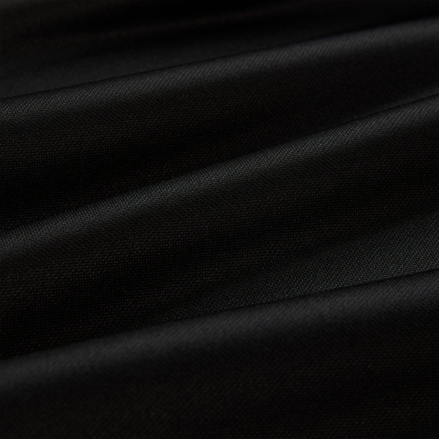 Close-up of black athletic polyester fabric with subtle folds, showing its smooth texture.