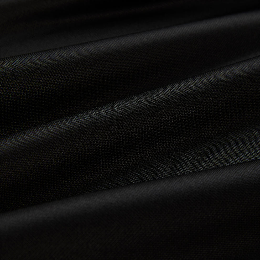 Close-up of black athletic polyester fabric with subtle folds, showing its smooth texture.