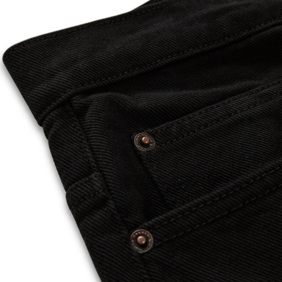 Close-up of black V3 denim pants with custom branded hardware and belt loops.