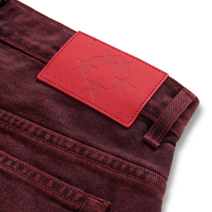 Faded wash red denim pants with a branded red leather back patch featuring star designs.