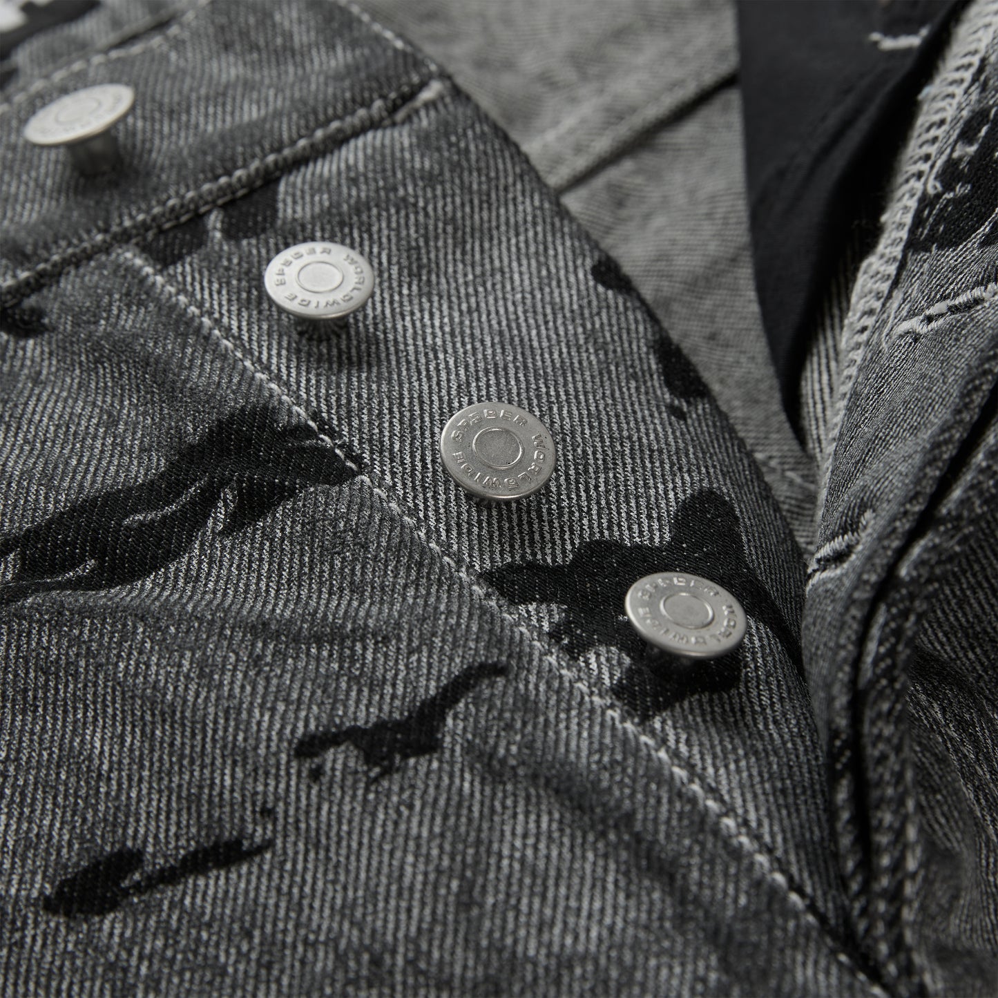 Washed black denim pants with an all-over print, branded silver hardware, and red contrast stitching.