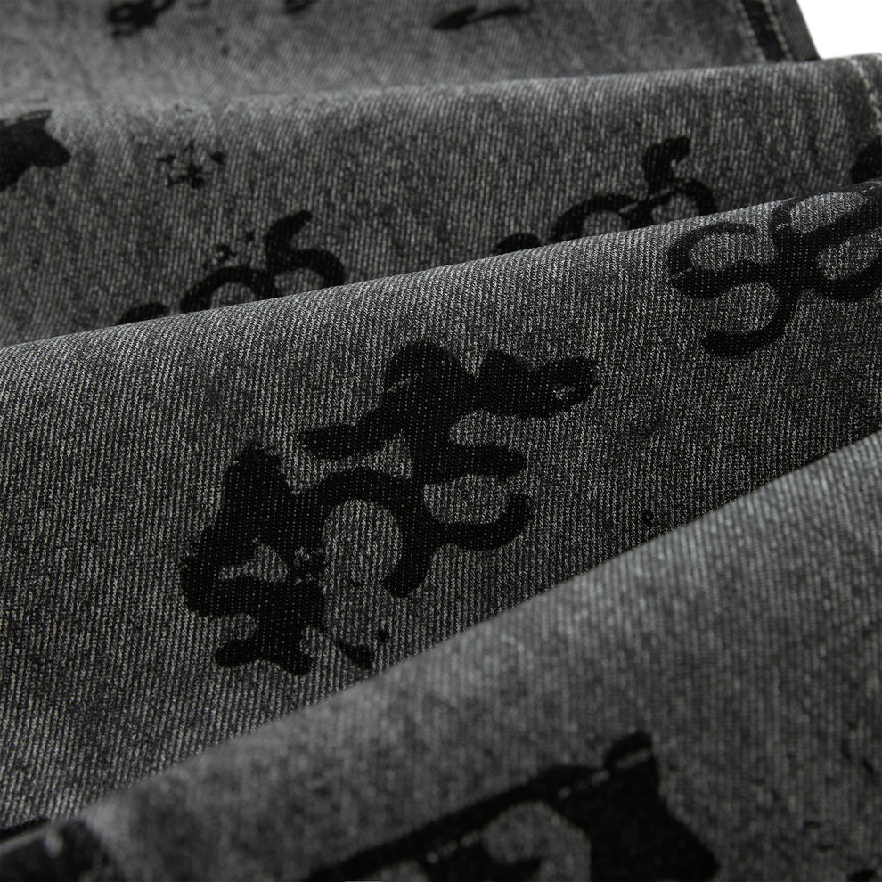 Gray denim pants with black all-over print design and red contrast stitching.