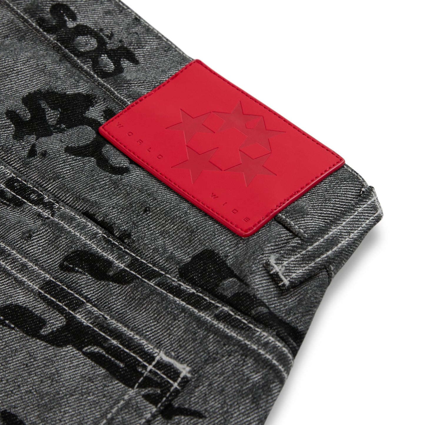 Grey denim pant with black all-over print, red leather branded patch, and red contrast stitching.