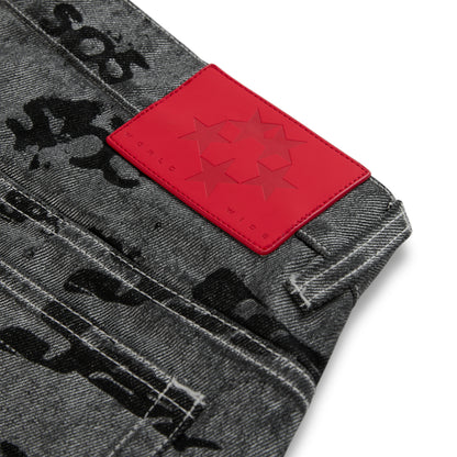 Grey denim pant with black all-over print, red leather branded patch, and red contrast stitching.