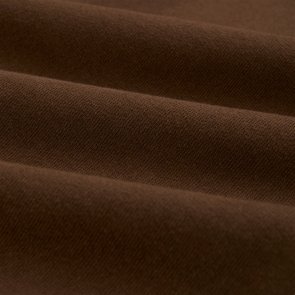 Close-up of brown 13oz cotton fleece fabric, showing its soft texture and folds.