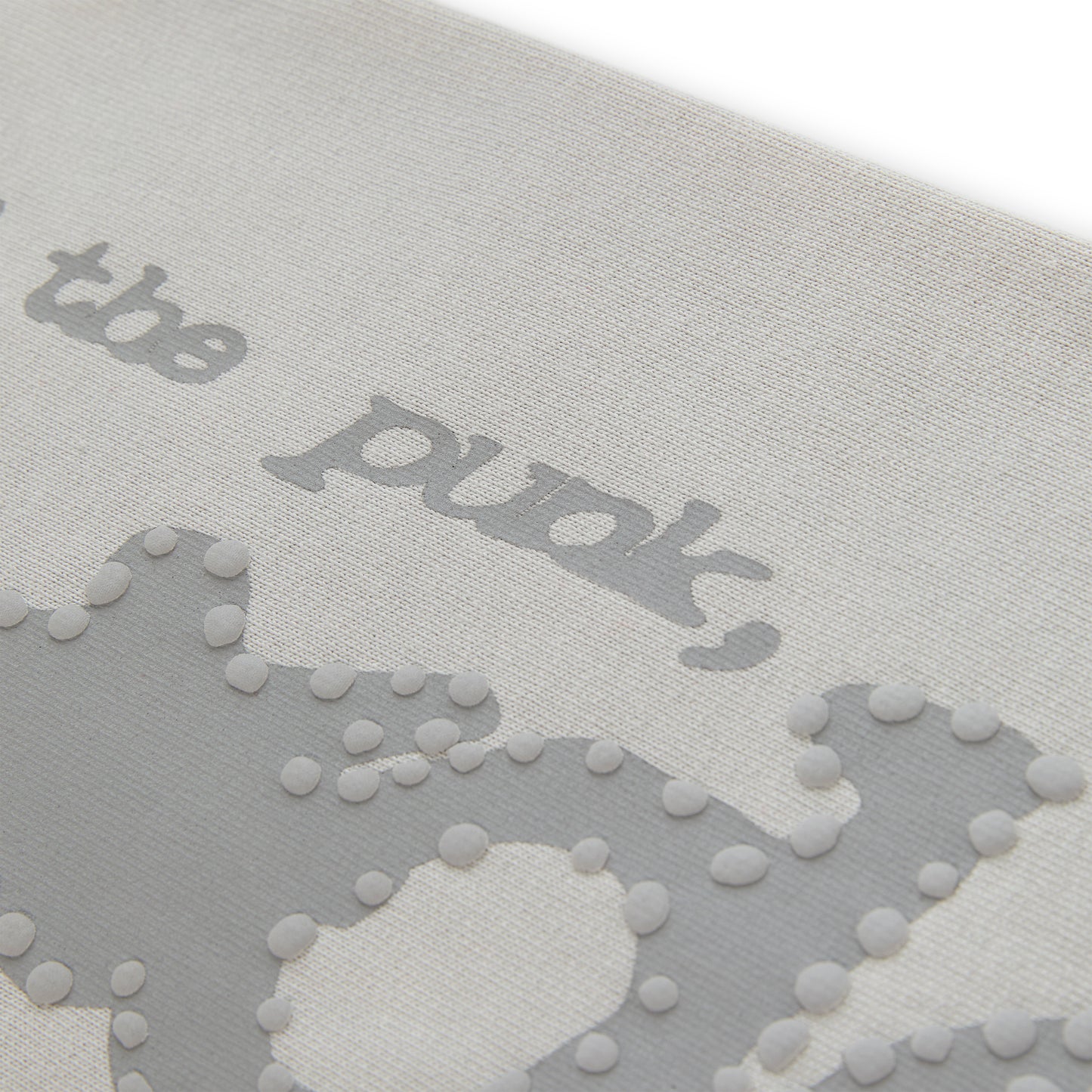 Close-up of light grey cotton fleece sweatpant with puff print "P*NK SP5DER" text and stars.