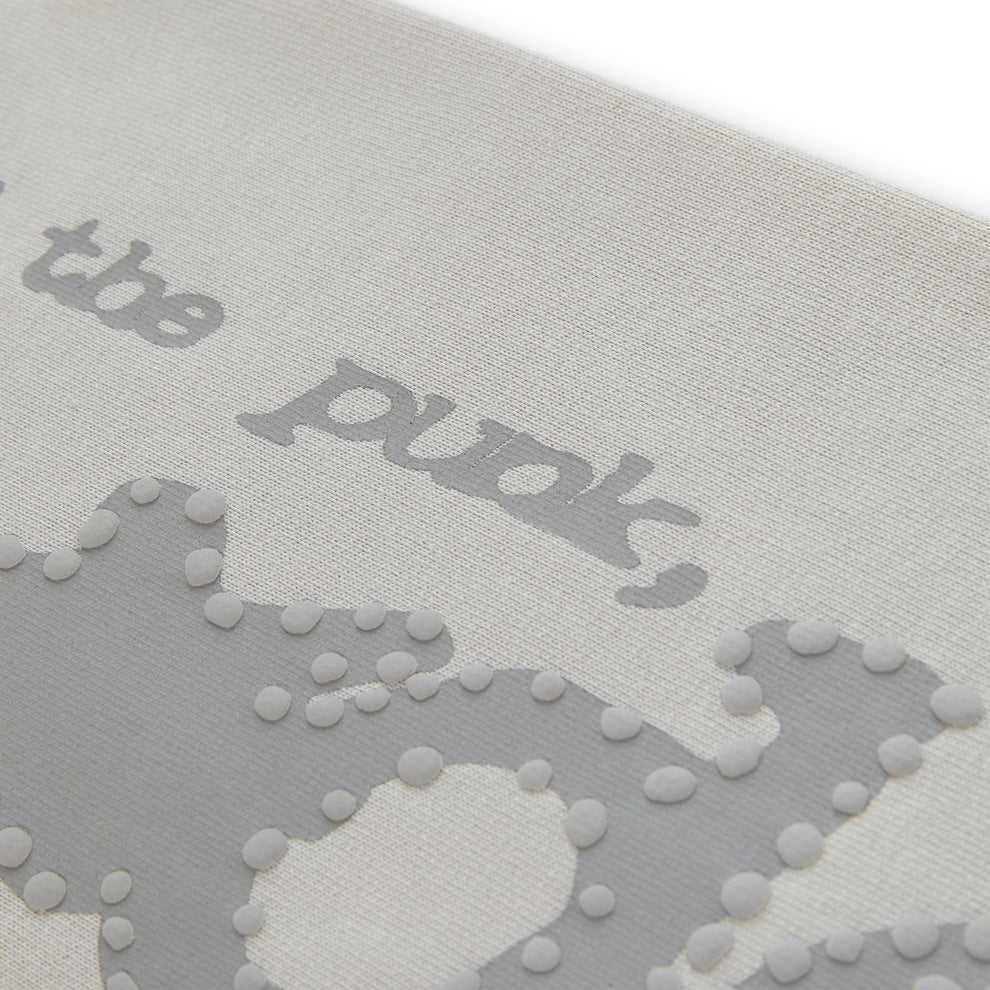 Close-up of light grey cotton fleece sweatpant with puff print "P*NK SP5DER" text and stars.