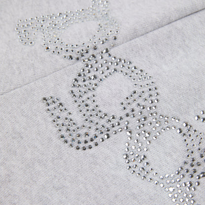 Close-up of gray cotton fleece sweatpants with "SP5DER" text and "5" star design in rhinestones.