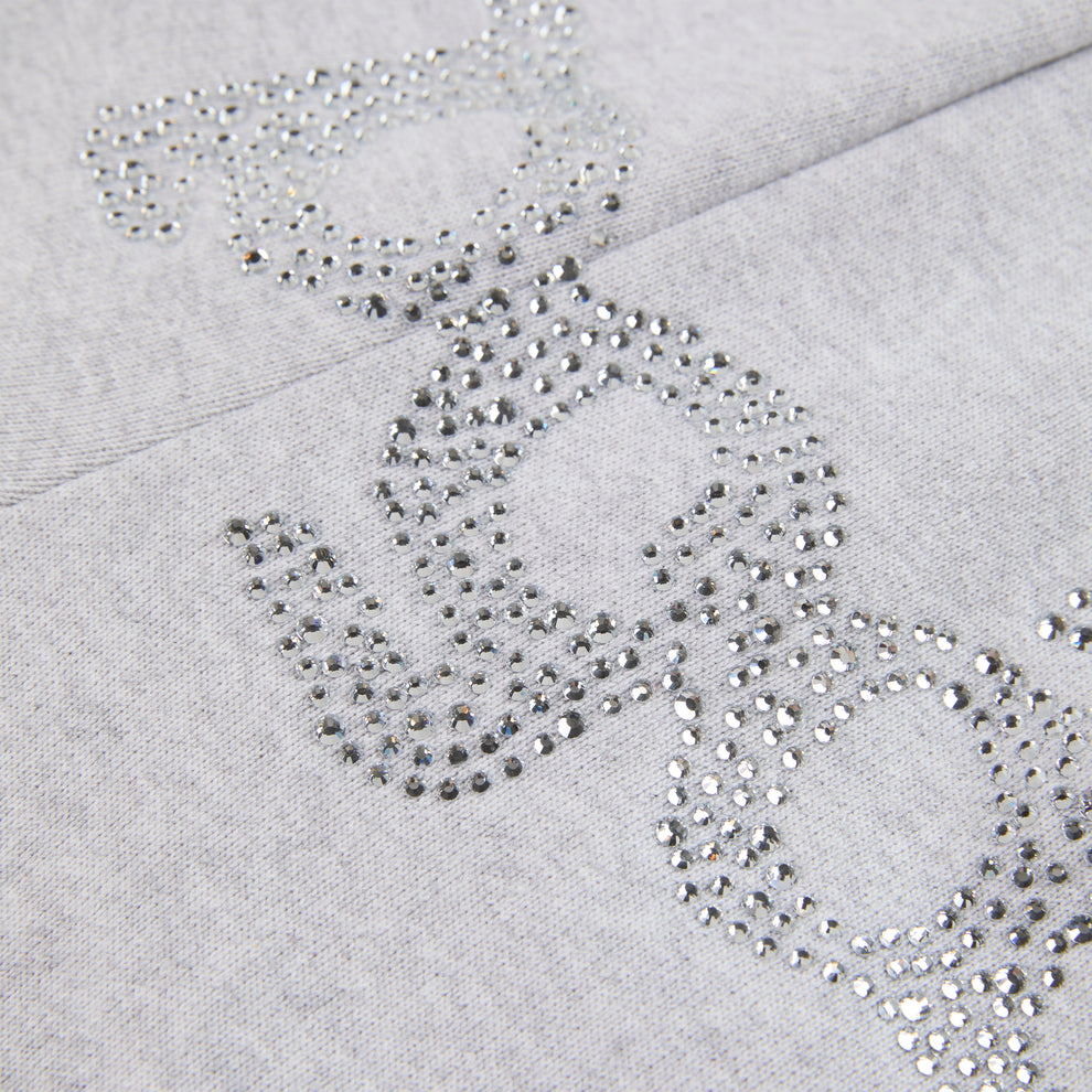 Close-up of gray cotton fleece sweatpants with "SP5DER" text and "5" star design in rhinestones.