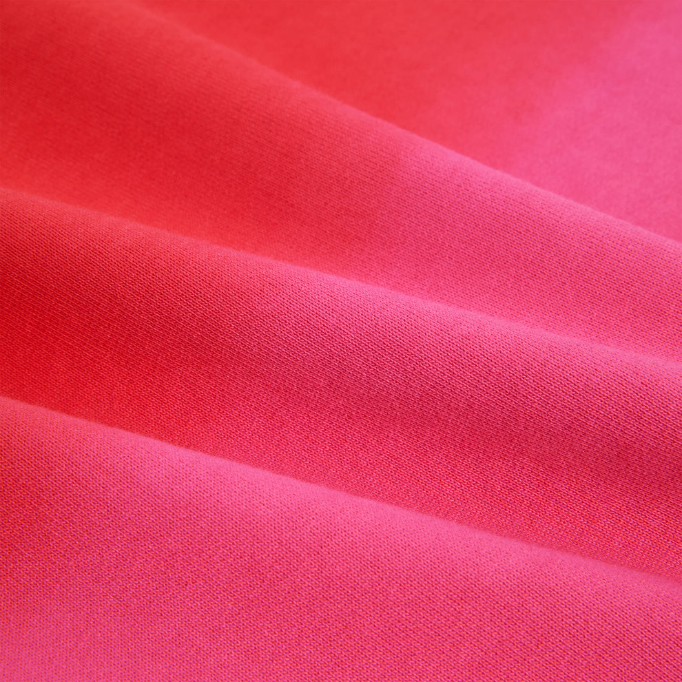 Close-up of a vibrant pink 100% cotton brushed fleece fabric with subtle folds, showcasing its soft texture.