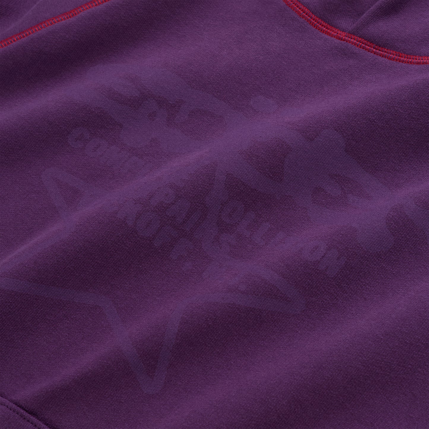 Purple 13oz cotton fleece hoodie with subtle graphic print and red contrast stitching.