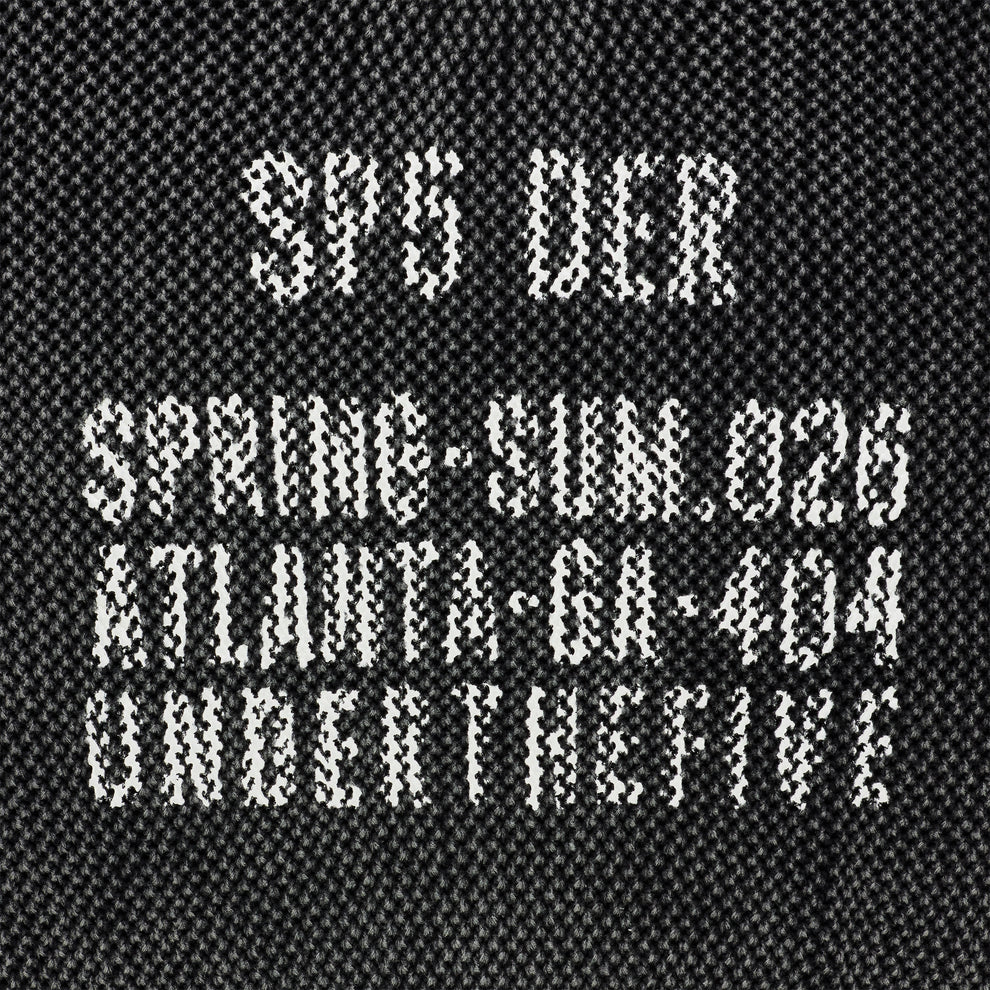 Black knit cotton sweater with white "UNDERTHEFIVE" text print and other details at chest.