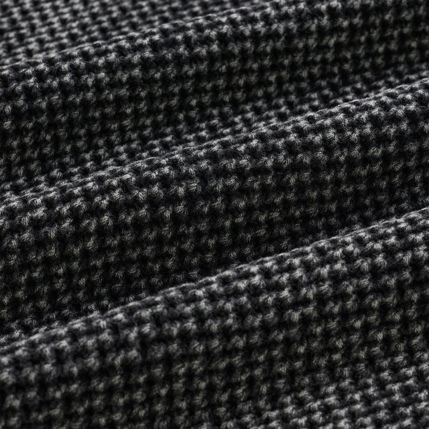 Close-up of a black and white knit cotton sweater with a textured waffle weave.