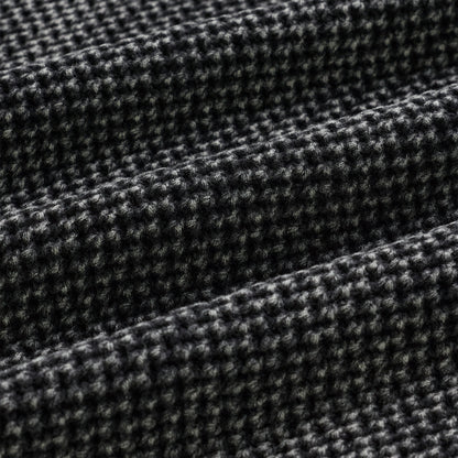 Close-up of a black and white knit cotton sweater with a textured waffle weave.