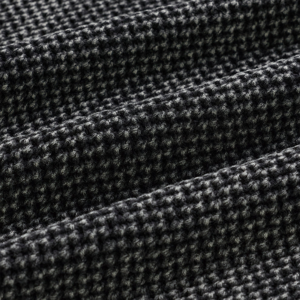 Close-up of a black and white knit cotton sweater with a textured waffle weave.