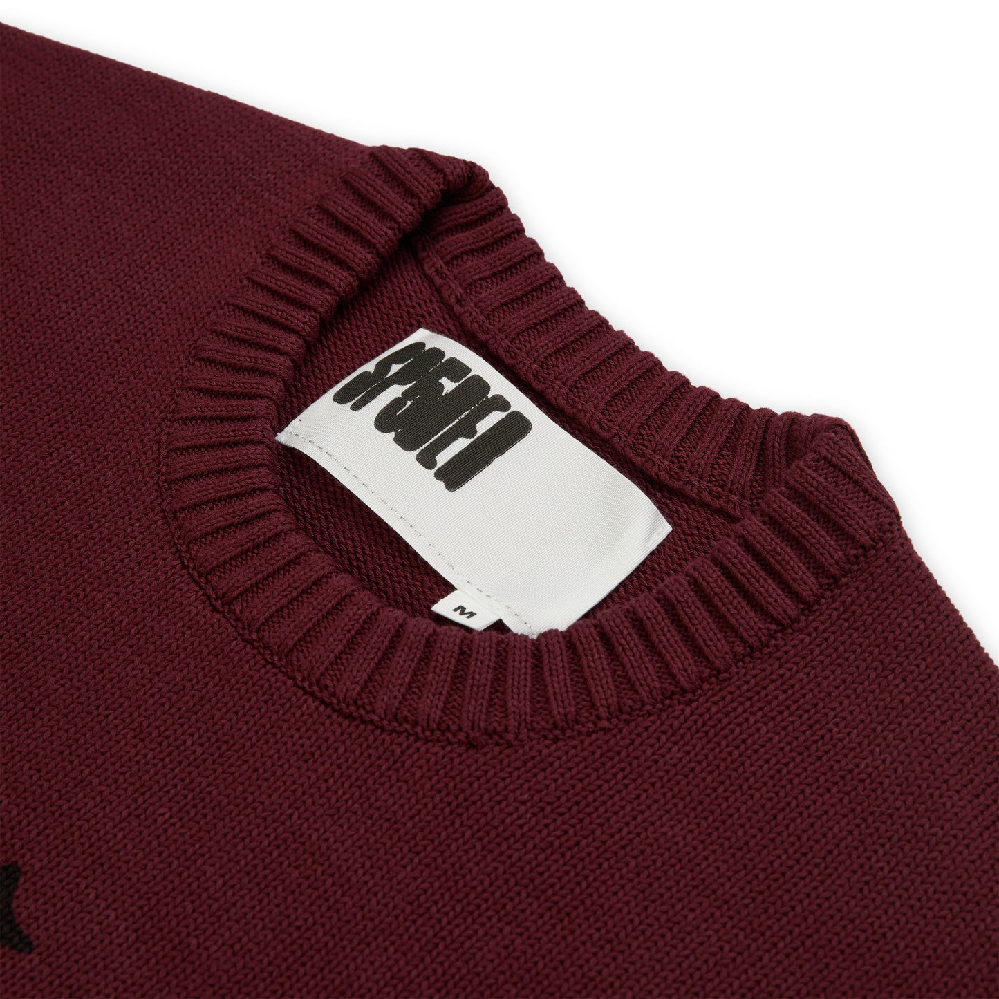 Maroon knit sweater with a ribbed collar and a white neck label featuring a black graphic print.