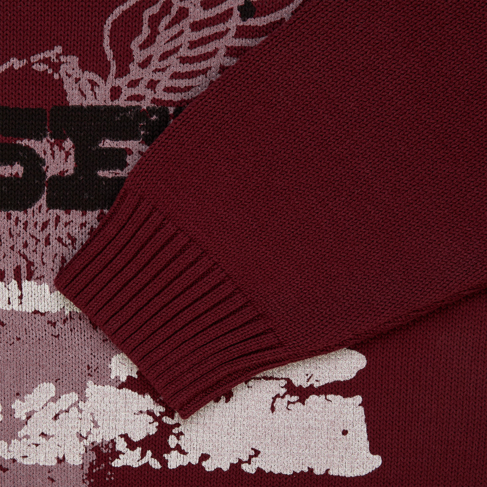 Maroon knit sweater with graphic print, ribbed cuffs, and textured fabric.