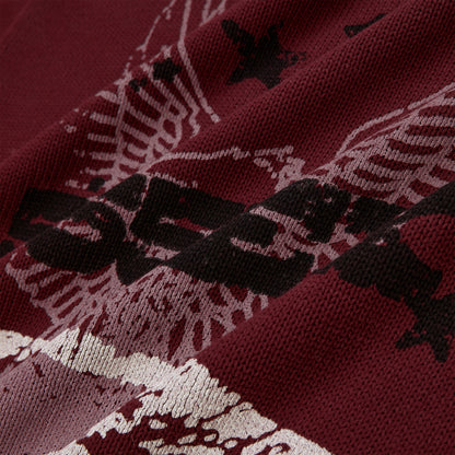 Close-up of a burgundy knit sweater with a black and white graphic print.