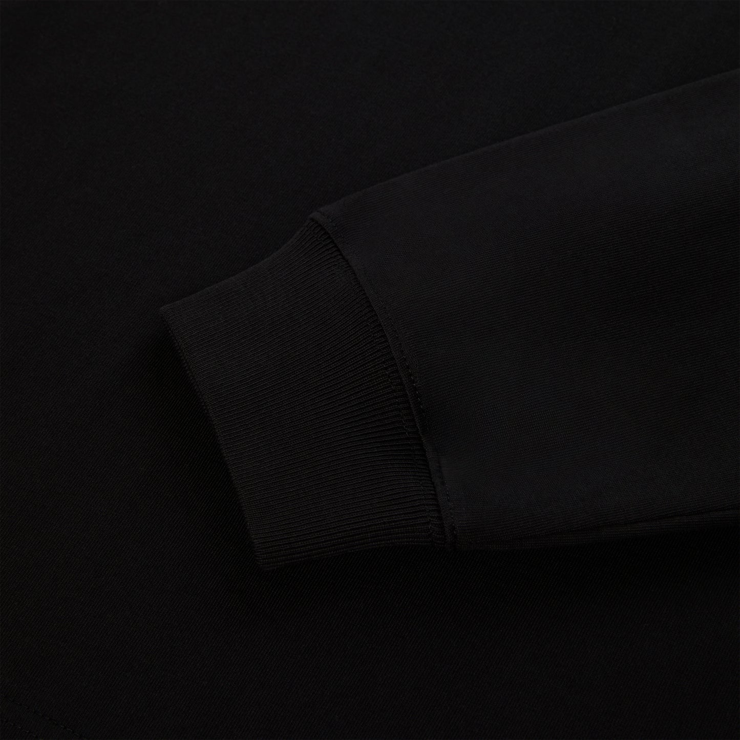Close-up of a black 555 SP5DER long sleeve's ribbed cuff and sleeve, 100% cotton.