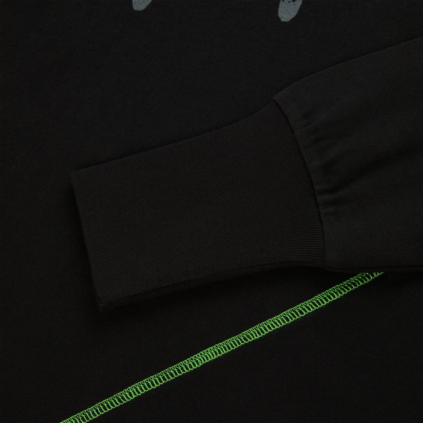 Black cotton long sleeve tee with ribbed cuff and bright green contrast stitching.