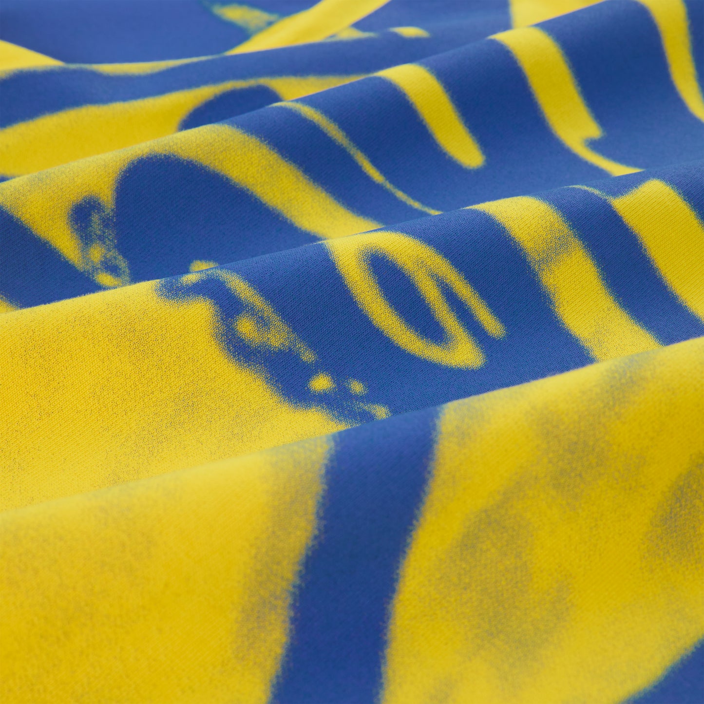 Close-up of SP5 Winners long sleeve tee, showing blue and yellow graphic print on cotton fabric.