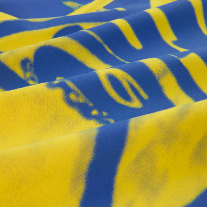 Close-up of SP5 Winners long sleeve tee, showing blue and yellow graphic print on cotton fabric.