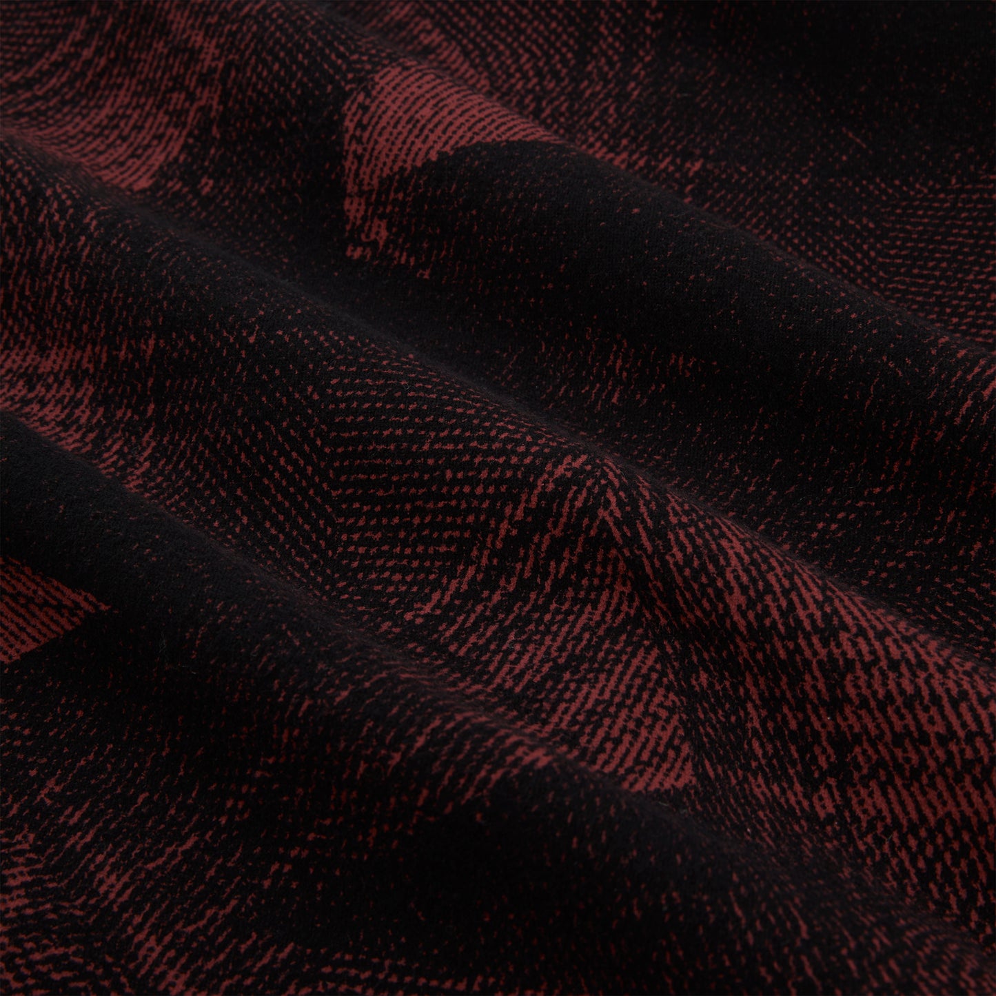 Close-up of black and red plaid cotton flannel fabric with SP5 graphic, showing soft texture and folds.