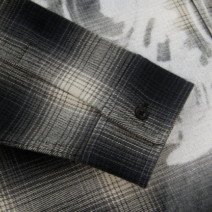 Close-up of a black and grey plaid cotton flannel shirt sleeve with a single-button barrel cuff.