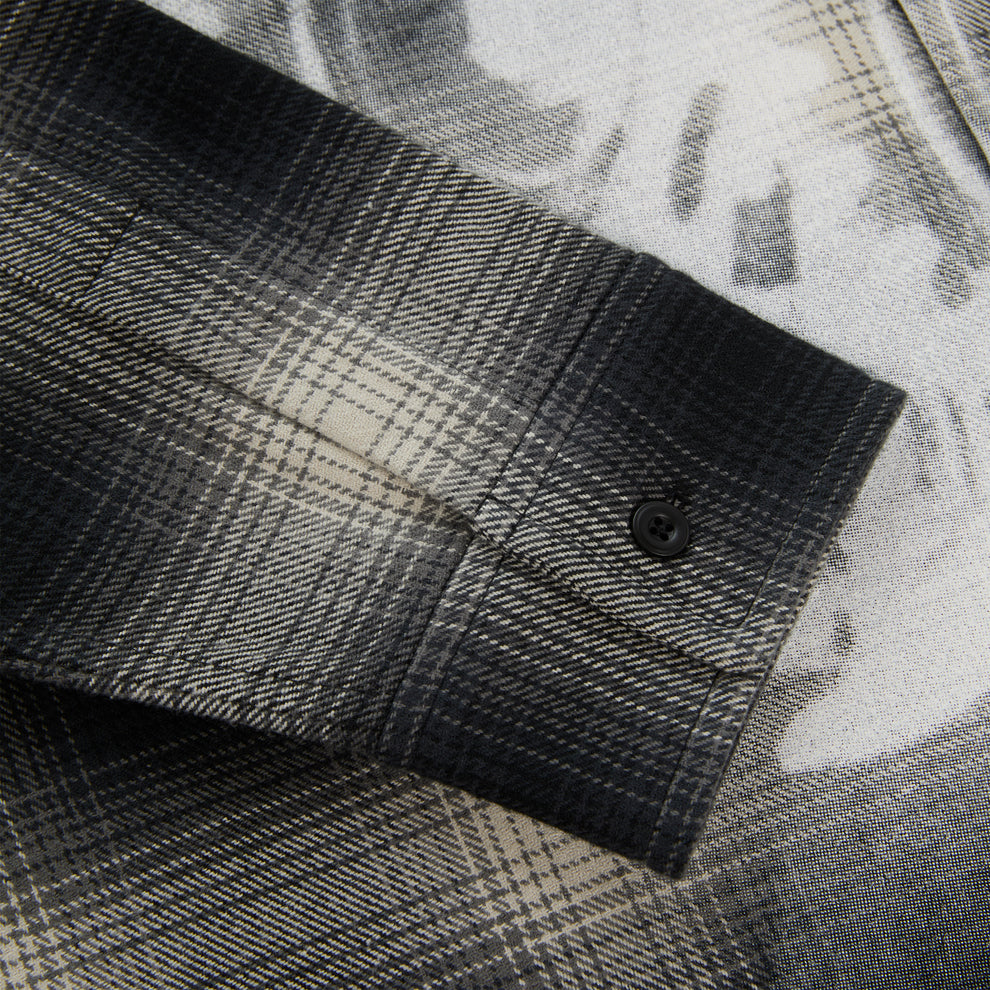 Close-up of a black and grey plaid cotton flannel shirt sleeve with a single-button barrel cuff.