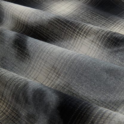 Close-up of a gray and cream cotton flannel shirt with a faded plaid graphic print.