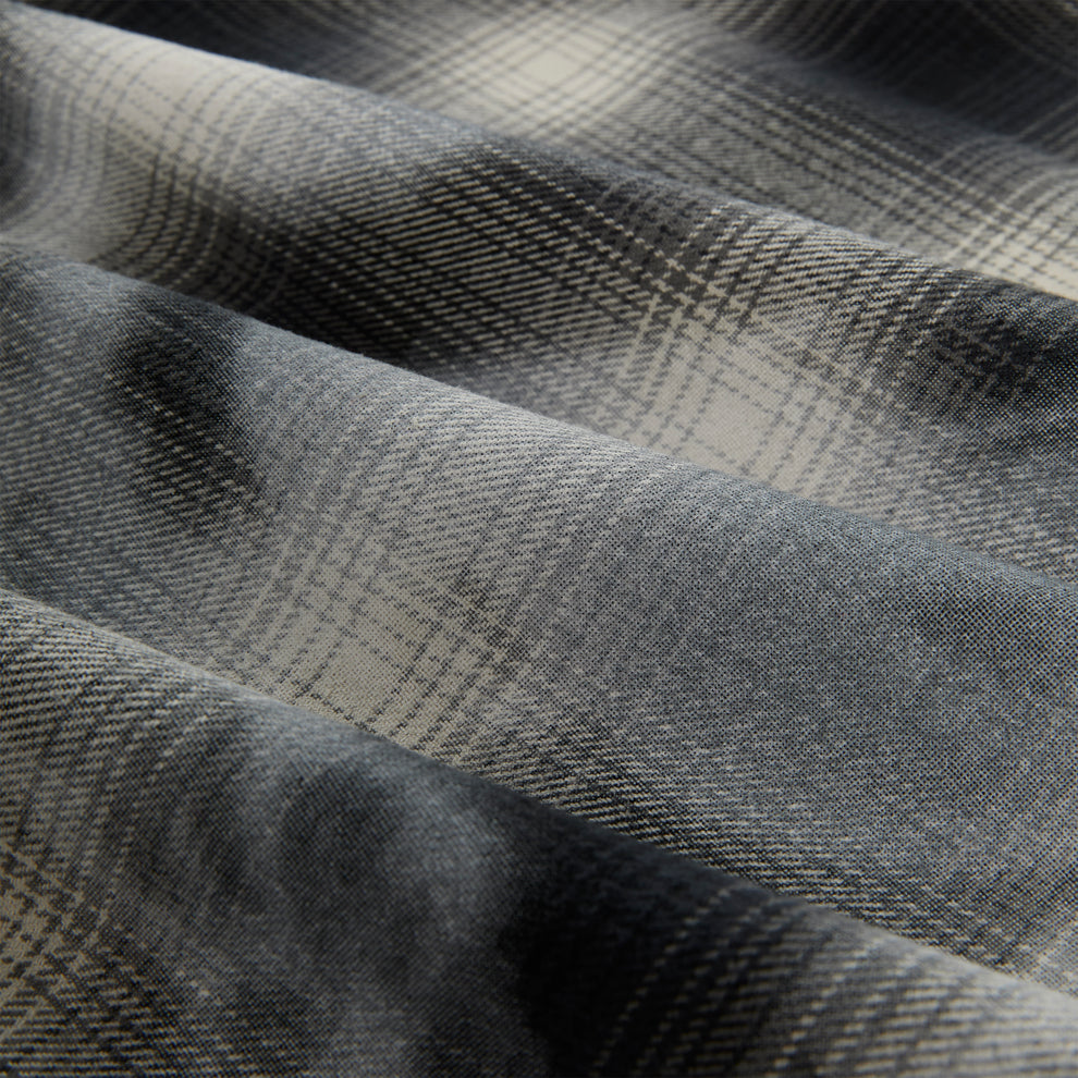 Close-up of a gray and cream cotton flannel shirt with a faded plaid graphic print.