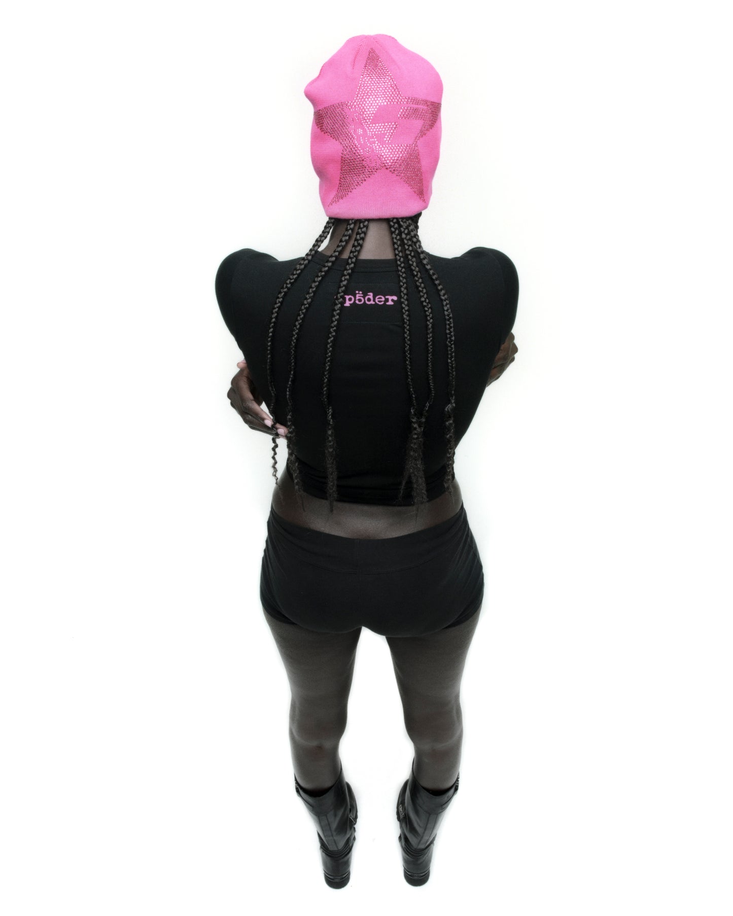 Black cropped MOTO 5 BABY TEE with pink 'SP5DER' logo on back neck, worn with black shorts and boots.