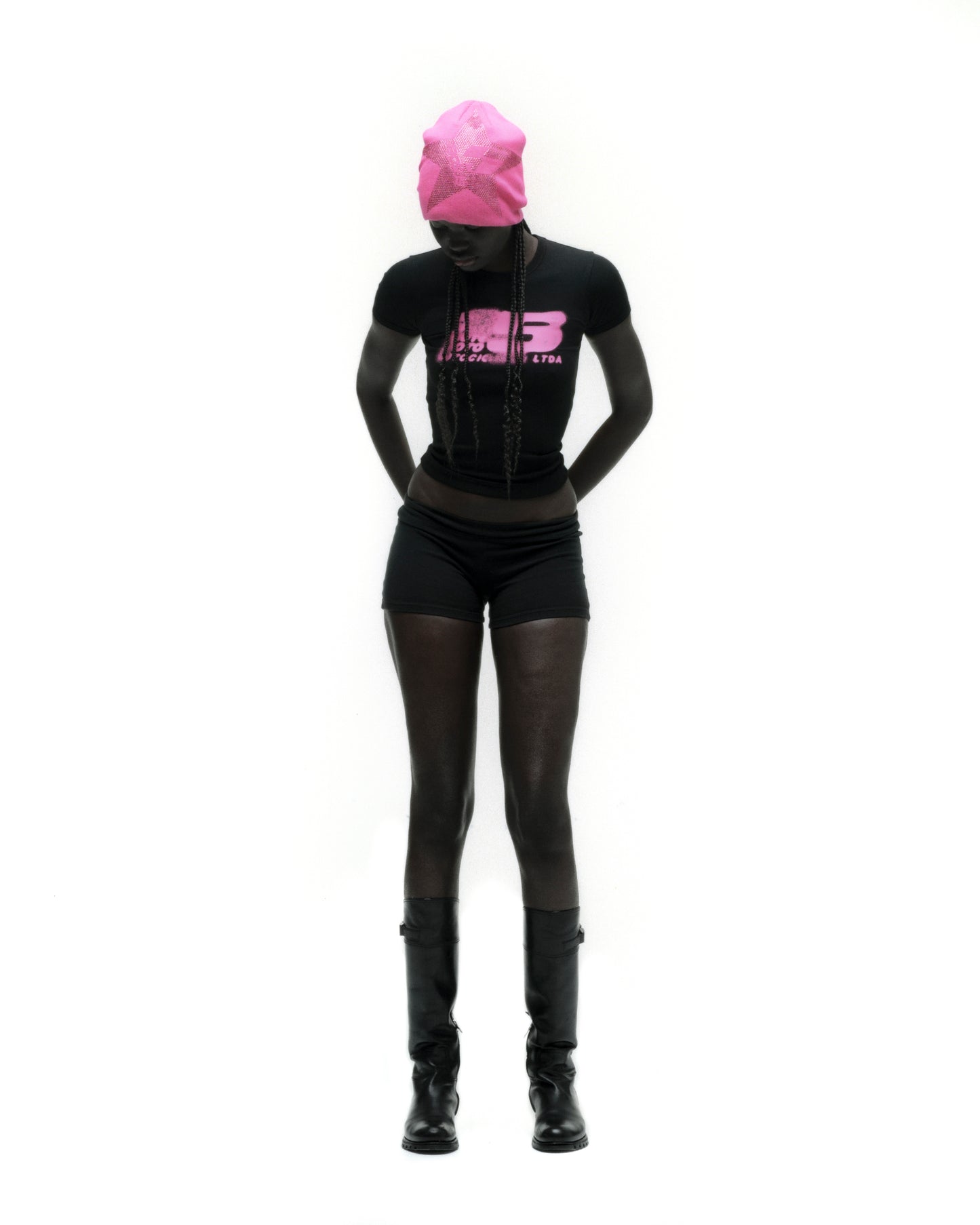 Black cropped MOTO 5 BABY TEE with pink graphic print, worn by a model with a matching pink beanie.