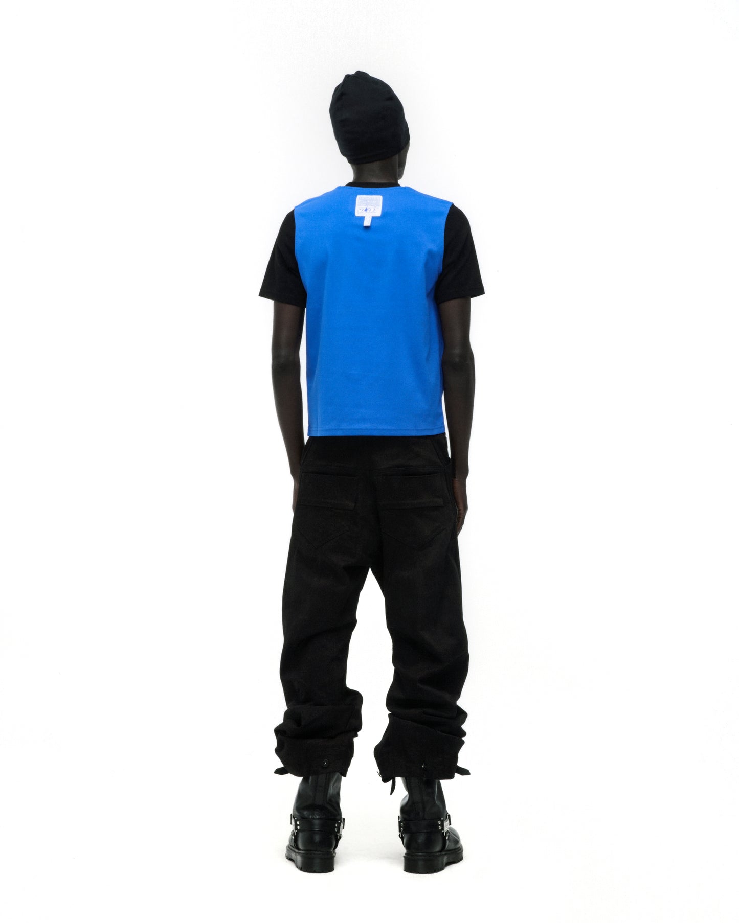 Black model wearing ENGINEER TEE: black shirt with blue vest overlay, black beanie, and black pants.