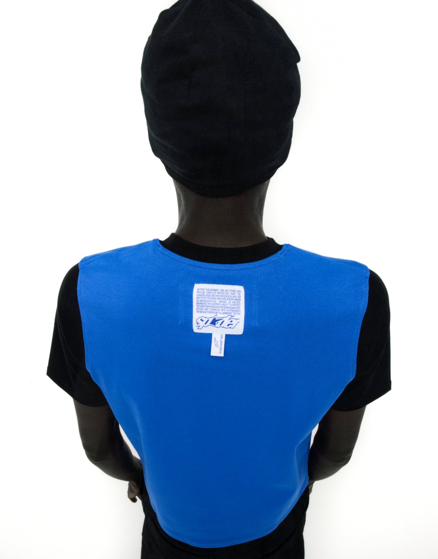Back of a person wearing a black Engineer Tee with a blue panel, white graphic, and woven logo label.