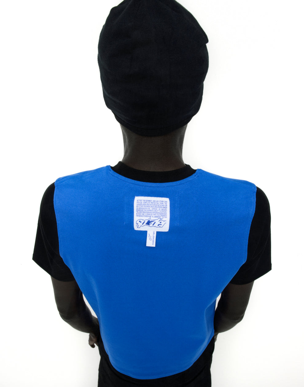 Back of a person wearing a black Engineer Tee with a blue panel, white graphic, and woven logo label.