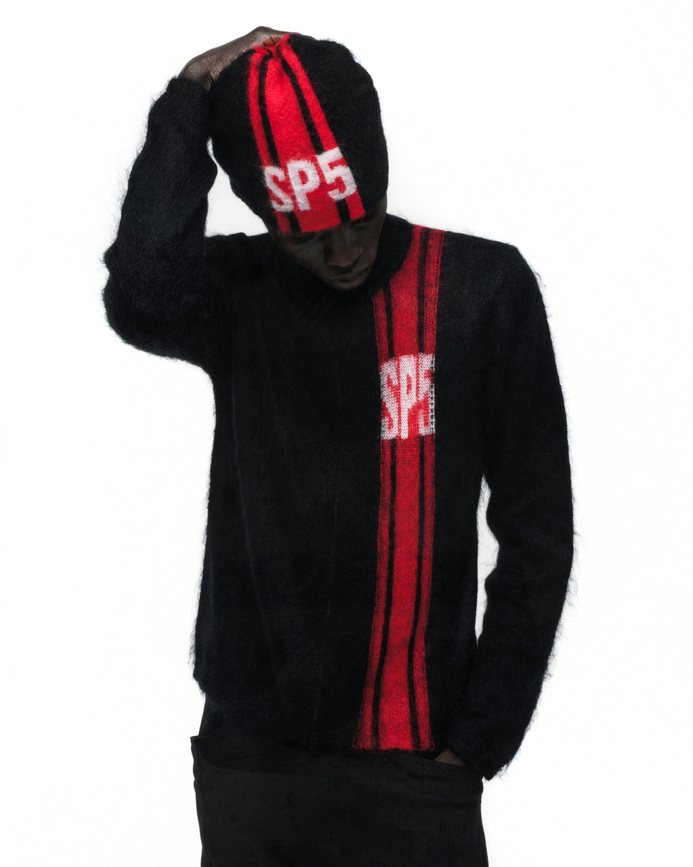 Black mohair knit zip sweater with red vertical stripe and "SP5" logo, worn by a model.