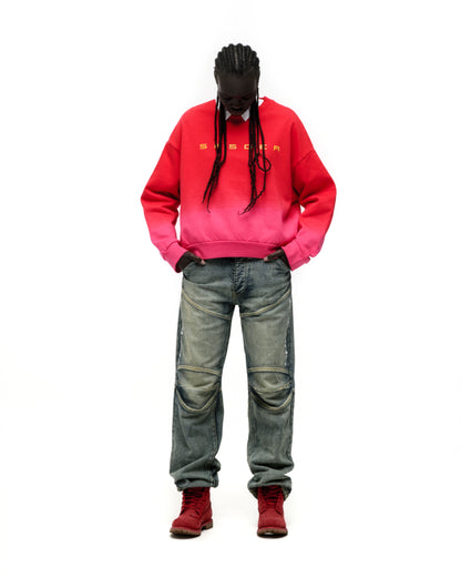 Red and pink gradient crewneck sweatshirt with yellow SP5DER text, worn with distressed jeans and red boots.