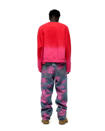 Man from behind wearing a red to pink gradient crewneck and blue jeans with pink star patterns.