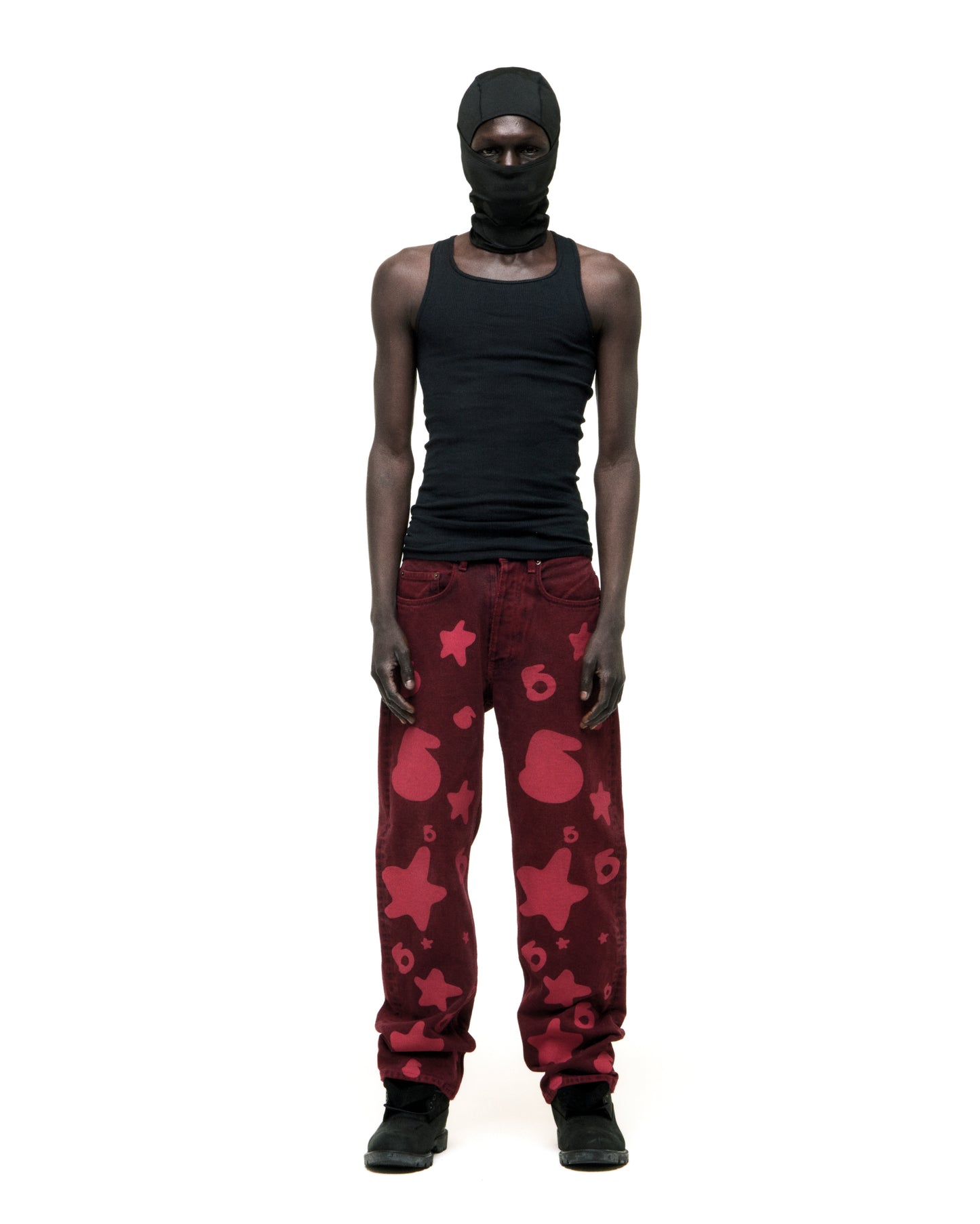 Model wearing faded wash Beluga print red denim pants with custom hardware and a branded leather patch.