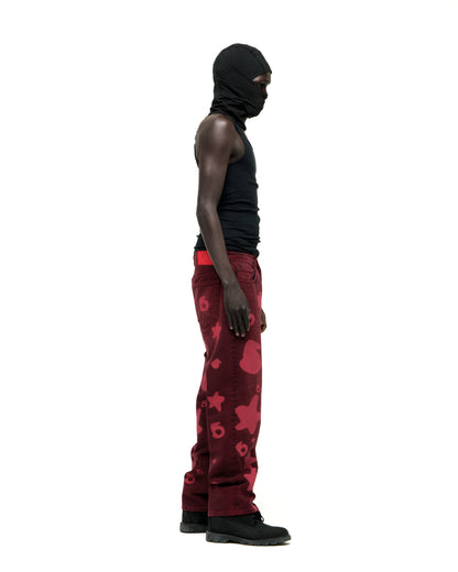 Man in black balaclava and tank top wearing faded red denim pants with Beluga print, custom hardware, and straight leg fit.