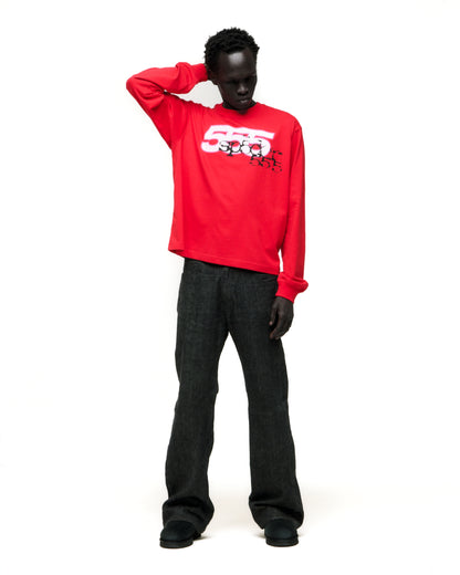 Model wearing a red 555 SP5DER cotton long sleeve tee with graphic print and dark jeans.