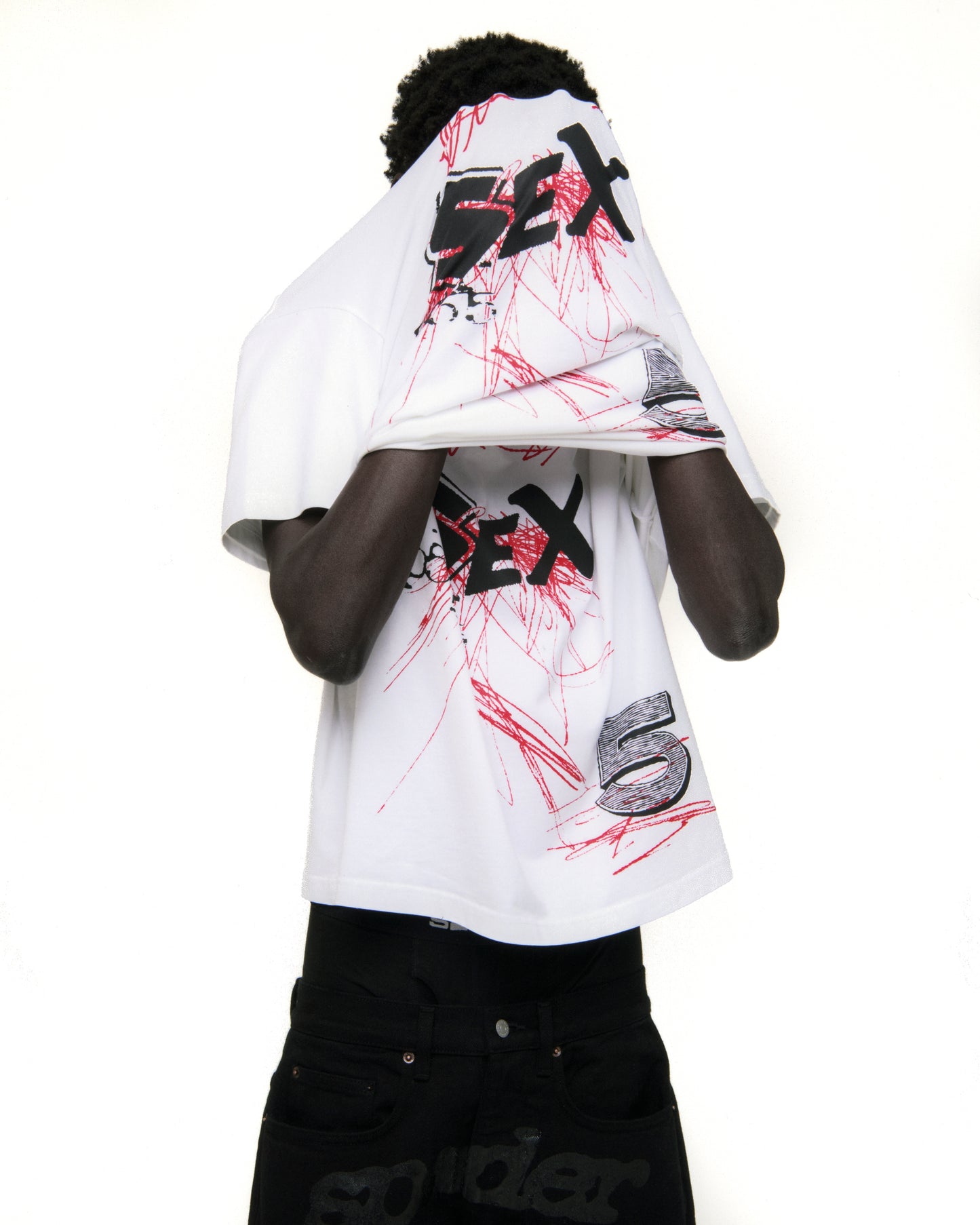 White cotton VIVIENNE TEE with black "SEX" graphic and red scribbles, worn by a person.