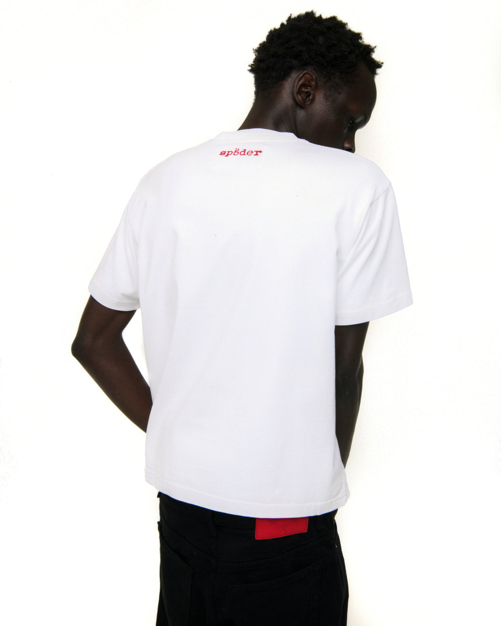 Back of a white cotton VIVIENNE TEE with red 'SP5DER' logo at the neck, worn by a person.