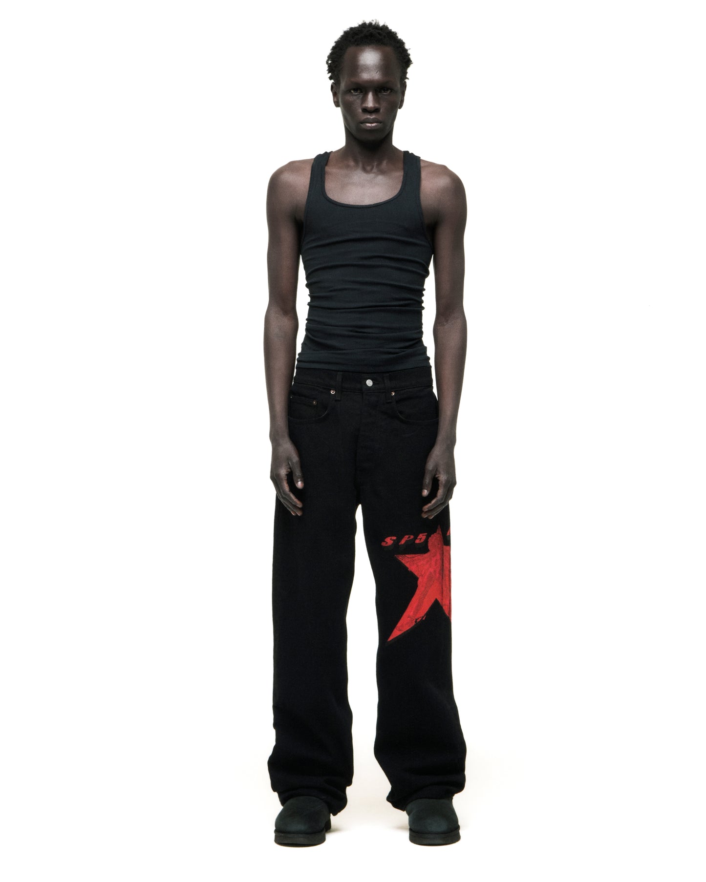 Black denim pants with a large red star graphic on the upper right leg and "SPG" text on the left.