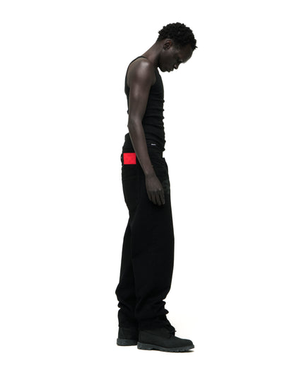 Man in black V3 DENIM pants, classic straight leg fit, with a red branded back patch.